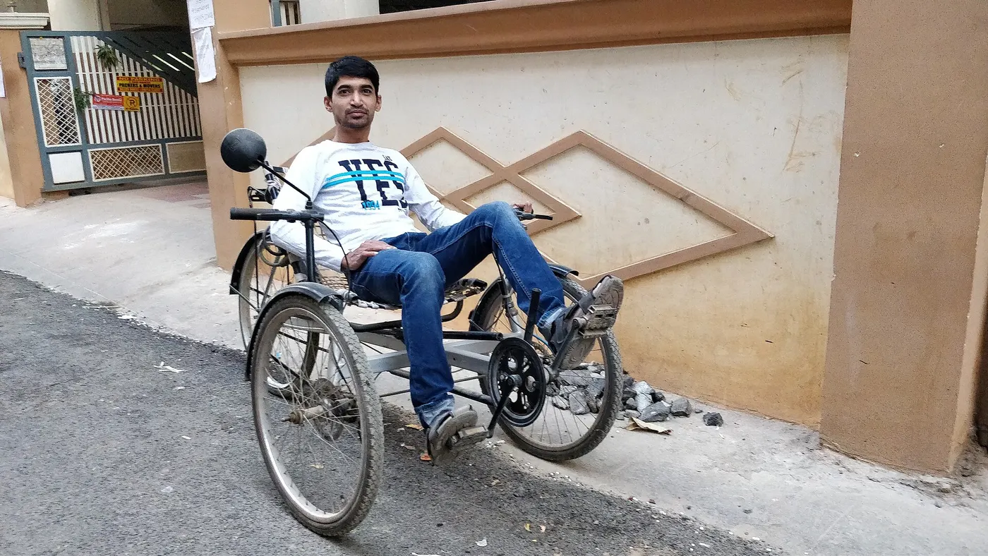A rider seated on a recumbent tricycle with pedals ahead of the body.